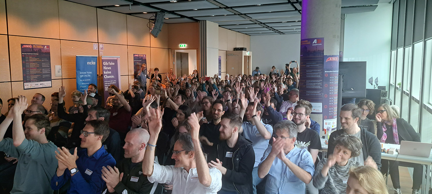 Publikum mit erhobenen Händen ca. 170 Personen von vorne